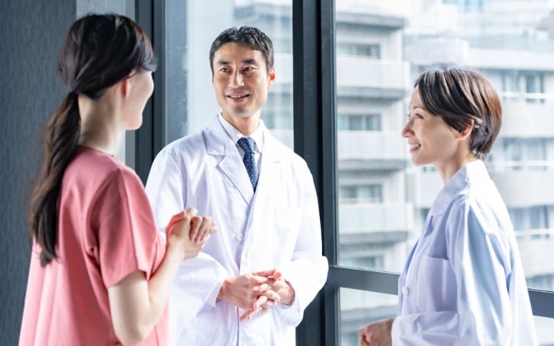 病院の窓際で話す男女の医師