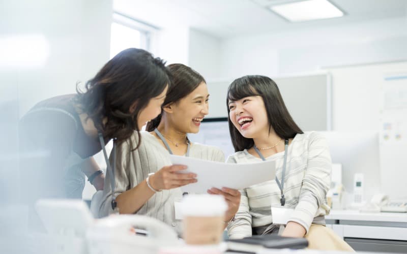 オフィスで笑顔でコミュニケーションする若い女性3人