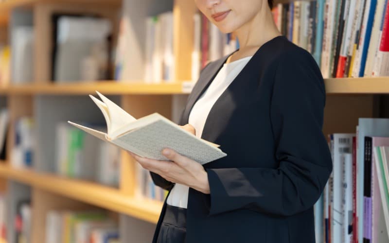 書棚の前で本を読む女性